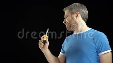 穿蓝色t恤的开朗英俊的男人拿着螺丝刀。 DIY、修理、初学者、业余建筑或家居装修
